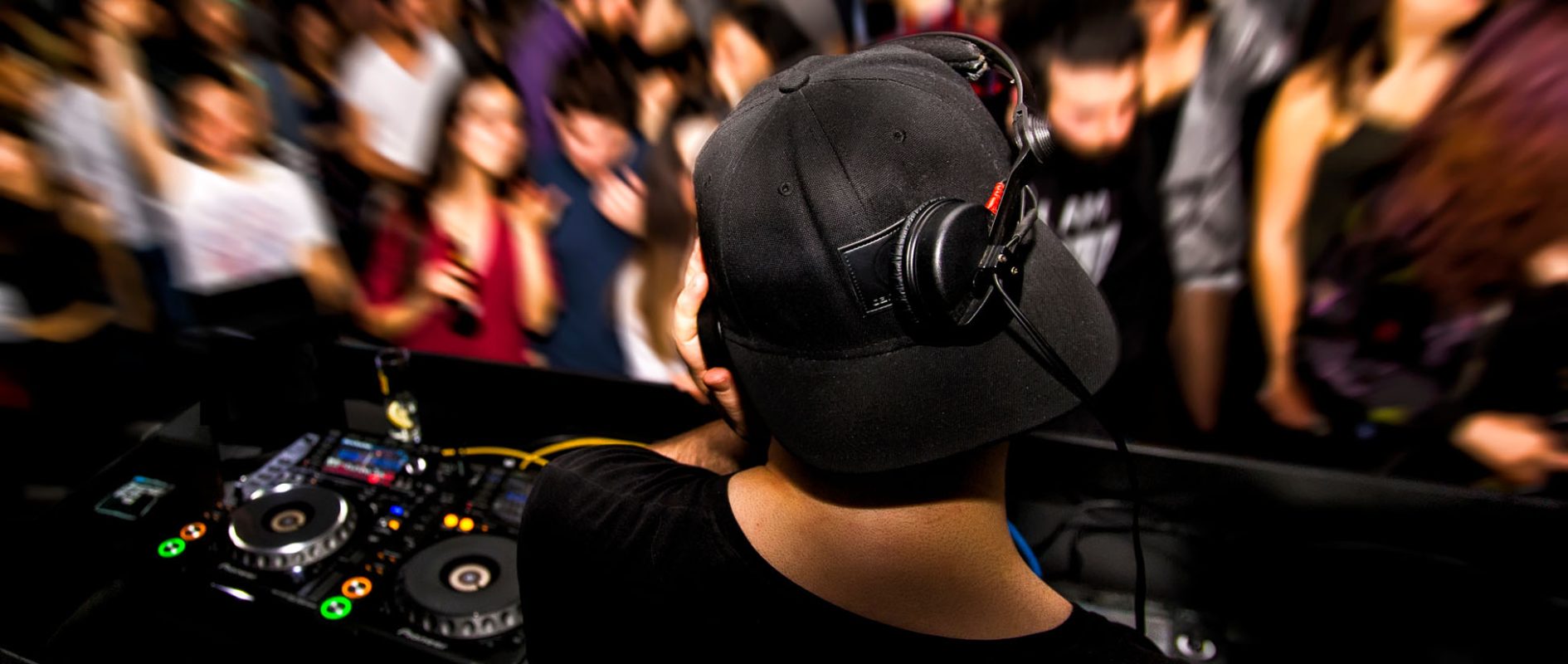 DJ with headphone and dj set at night club party. People at the